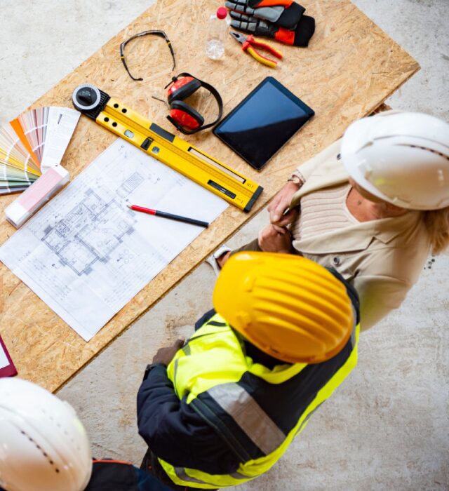 Construction workers reviewing blueprints on table.